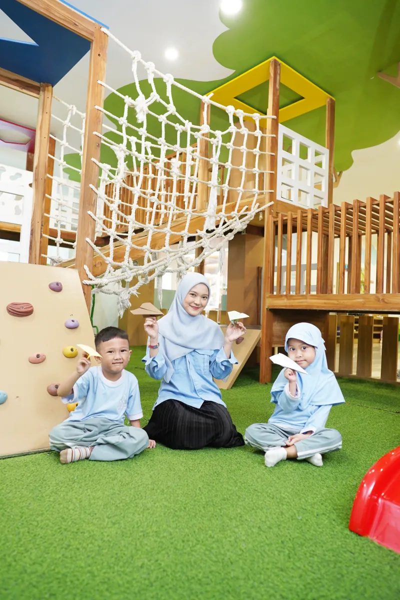 Guru dan anak duduk bersama di area playground