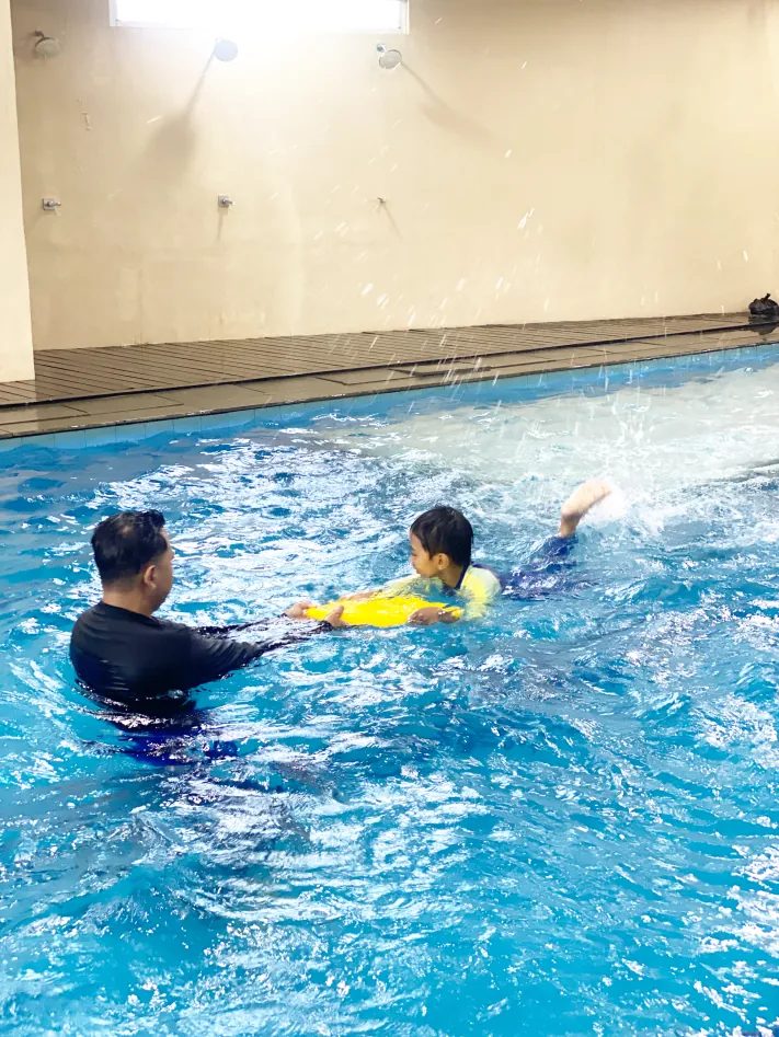 Coach mendampingi anak berenang