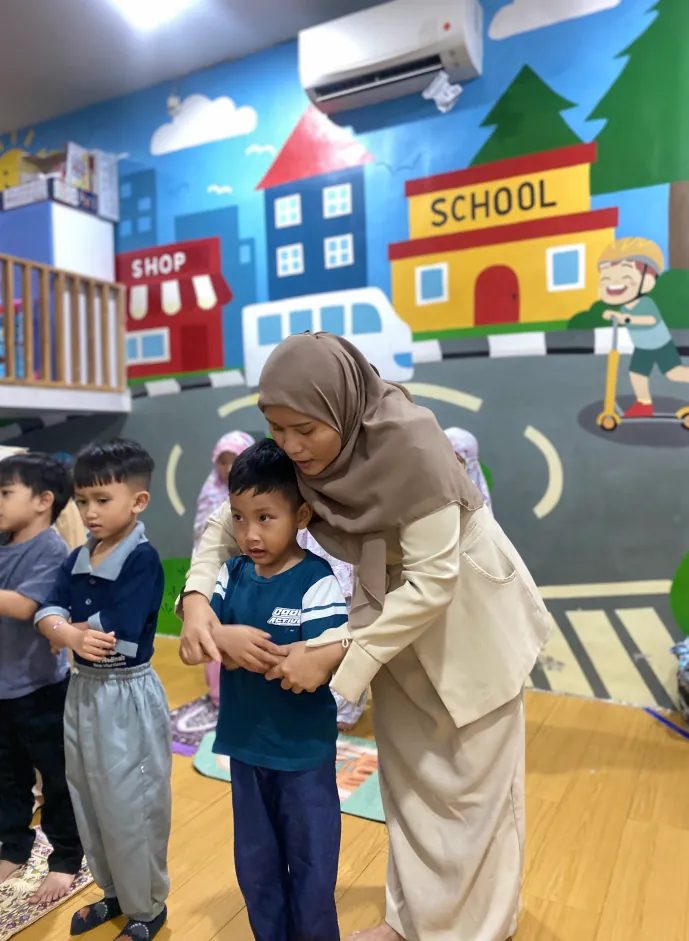 Pengasuh mendampingi anak di area bermain