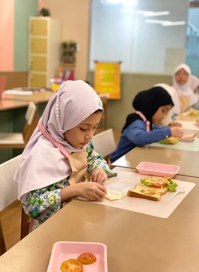 Siswi menyiapkan roti lapis di kelas memasak