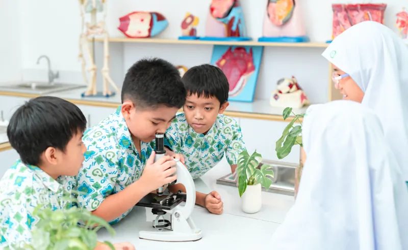 Siswa praktikum dengan mikroskop