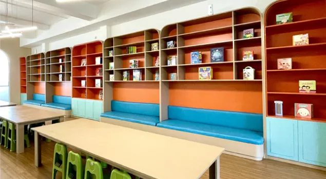Perpustakaan dengan rak buku oranye dan meja belajar anak